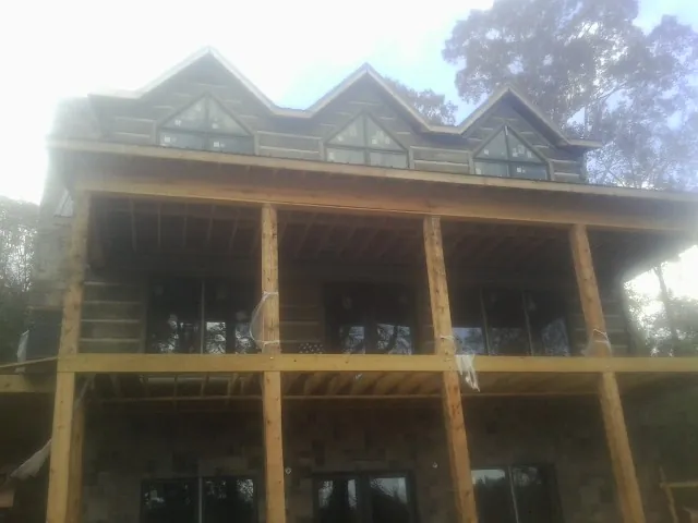 Dormers and porch framing on a large log home under construction — Roof Coating work by our crew in Selden