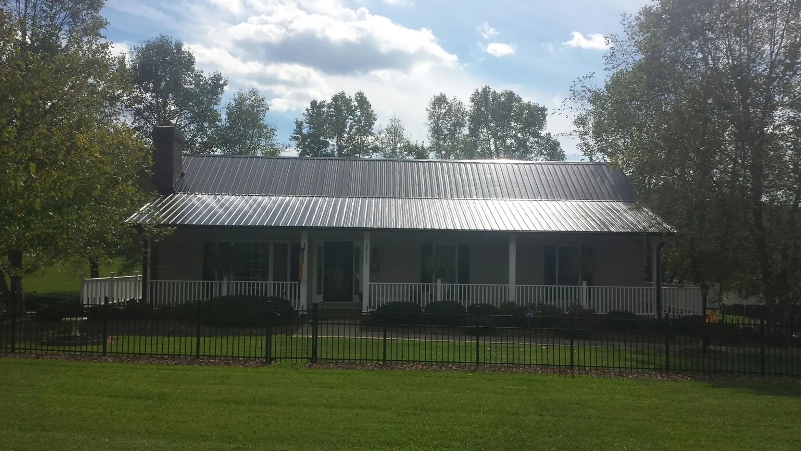 Gray metal roof on a brick ranch with a full width front porch — Gutter Guard Installation work by our crew in Selden