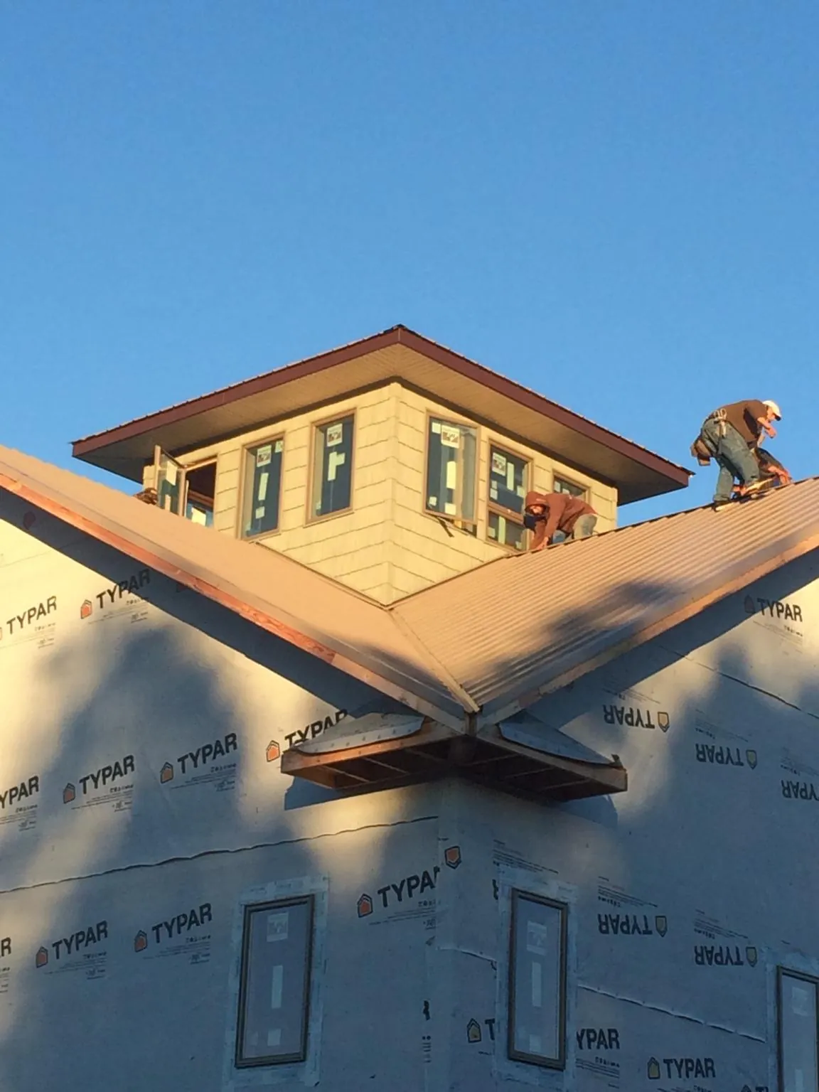 Roofers working around a rooftop cupola on a new metal roof at sunset — Roof Waterproofing in Selden by Roofing Brothers